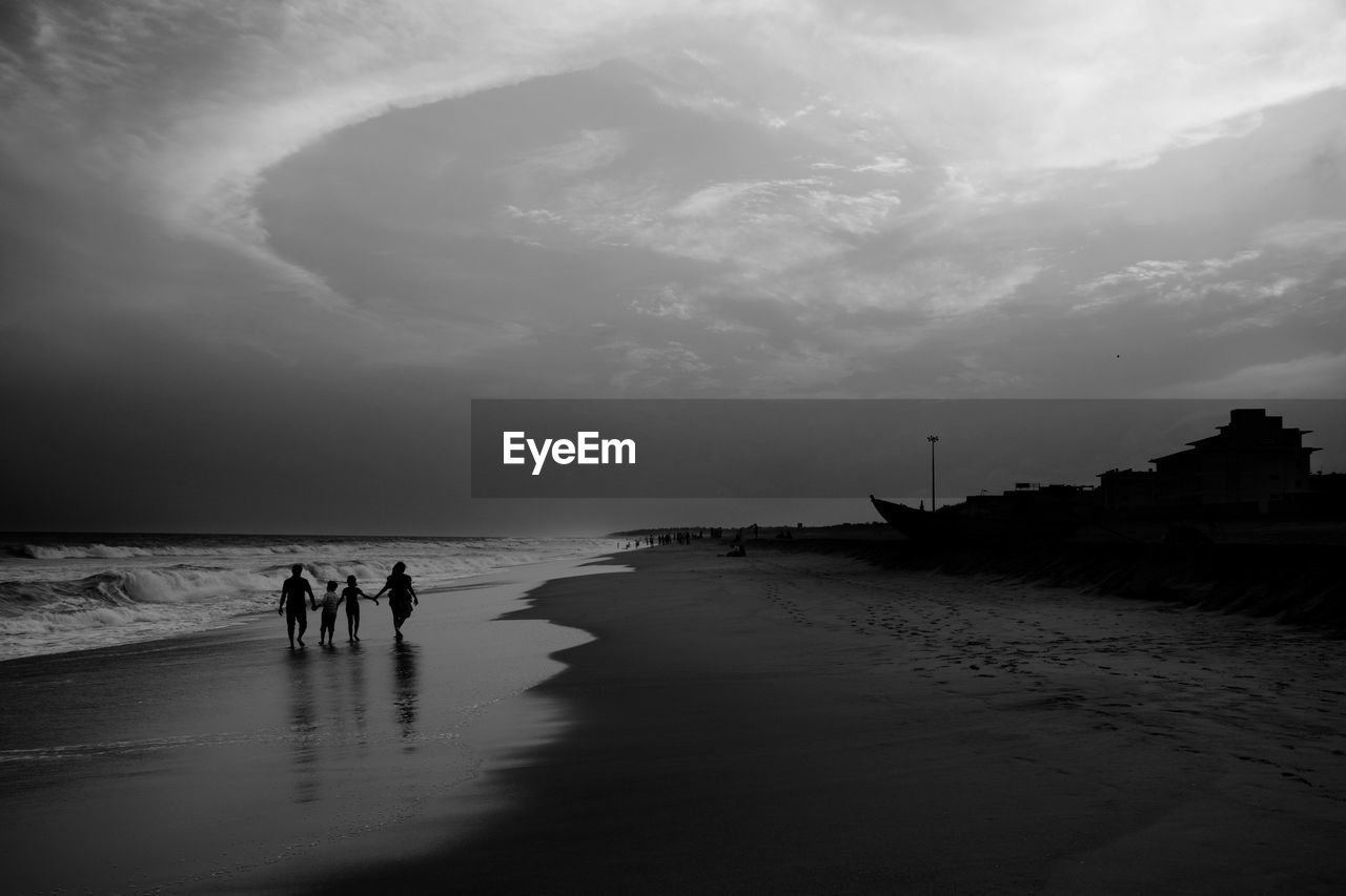 People walking at beach against sky