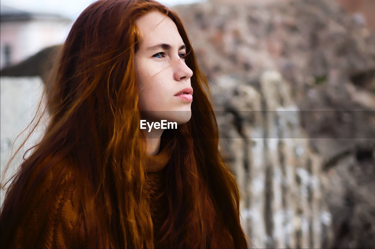 Thoughtful young woman with long brown hair looking away outdoors