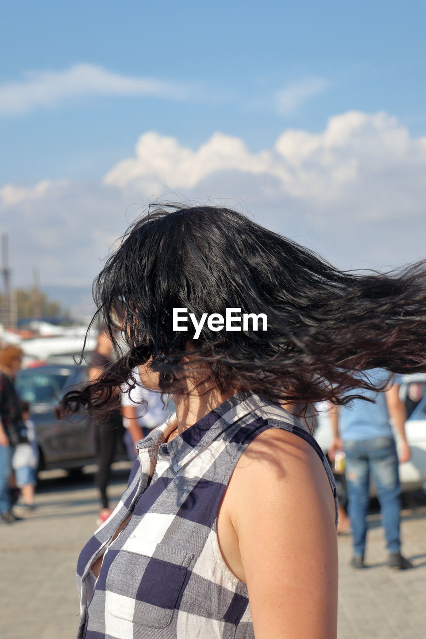 Woman tossing hair against sky