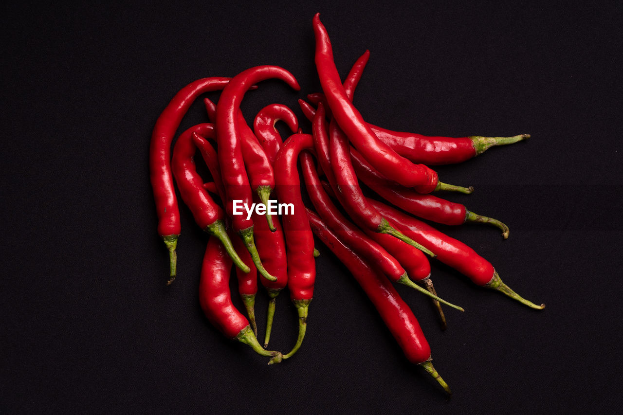 CLOSE-UP OF RED CHILI PEPPERS ON BLACK BACKGROUND