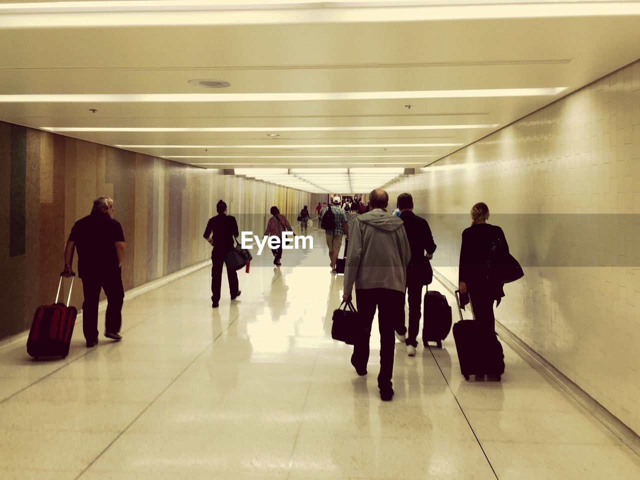 REAR VIEW OF PEOPLE WALKING ON ESCALATOR