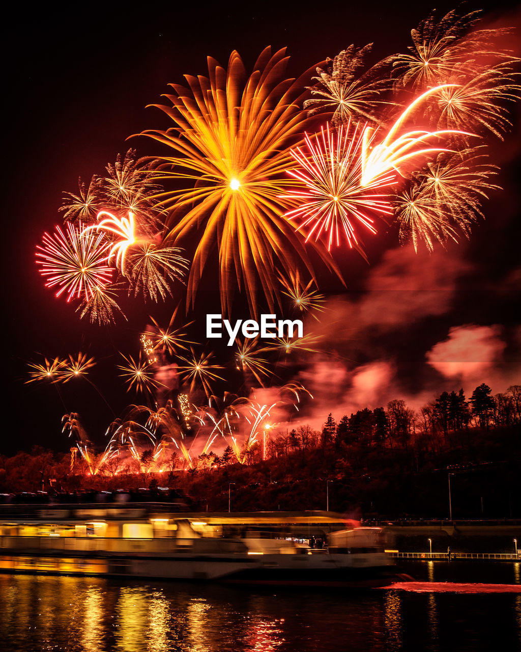 Low angle view of firework display over river against sky