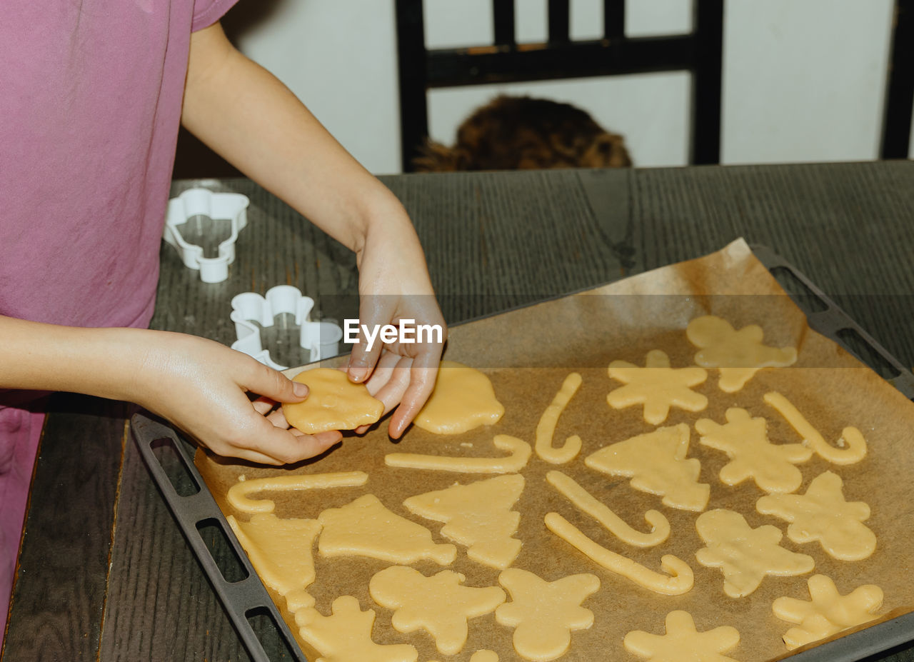 One girl bakes cookies, placing the dough on a baking sheet.