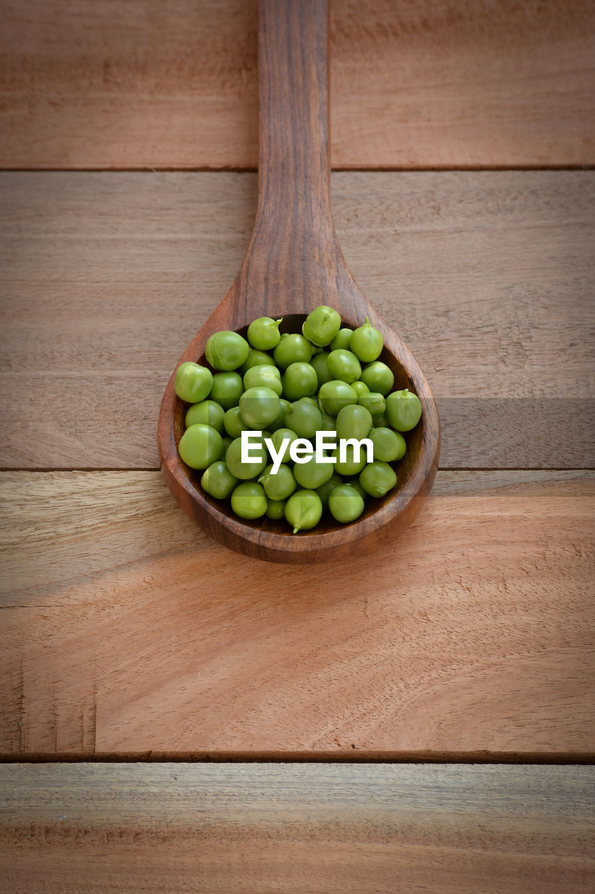 HIGH ANGLE VIEW OF GREEN FRUITS ON WOODEN TABLE