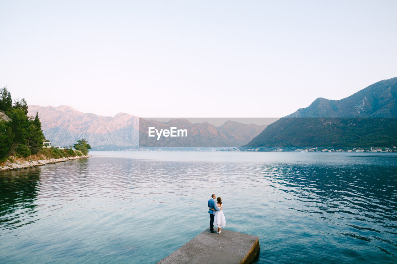 PEOPLE ON LAKE AGAINST MOUNTAINS