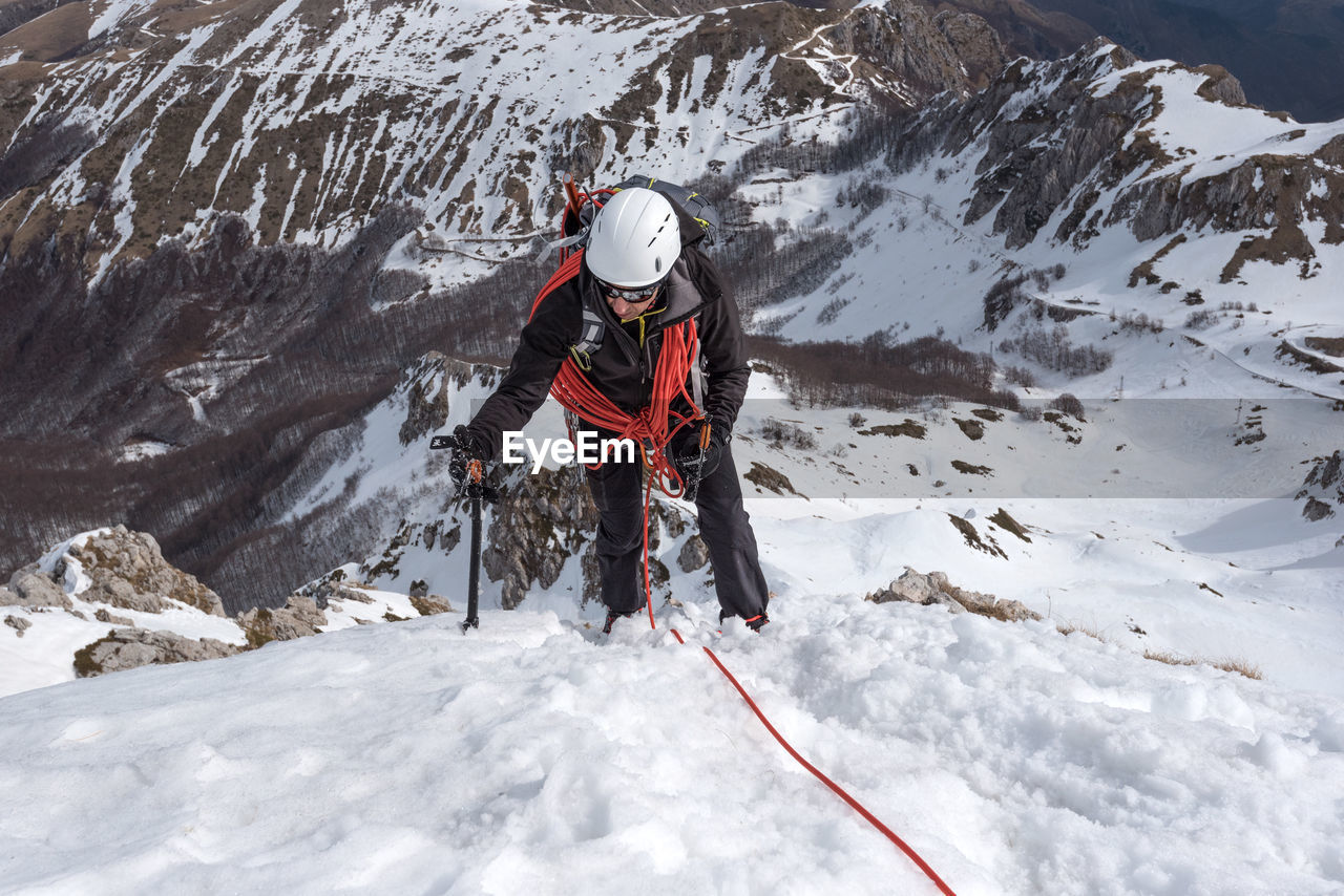 High angle view of man climbing snow covered mountain