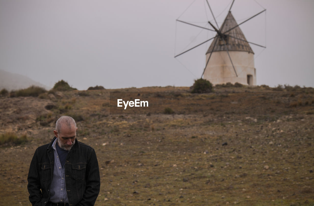 Adult man on fields against traditional windmill. cabo de gata nature park, almeria, spain