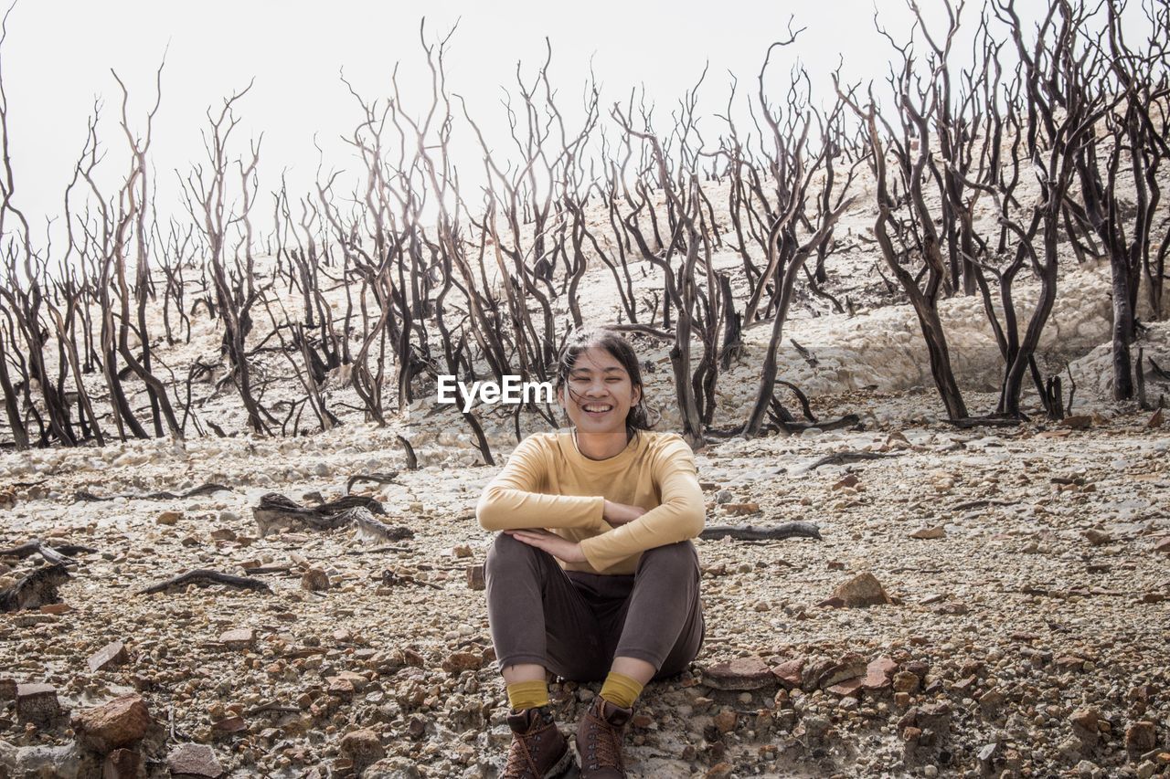 Smiling young woman sitting on landscape