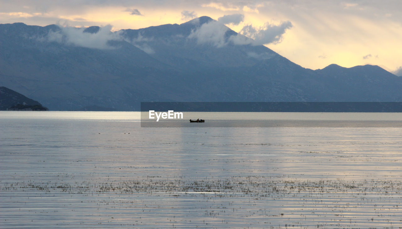 SCENIC VIEW OF SEA BY SNOWCAPPED MOUNTAINS AGAINST SKY