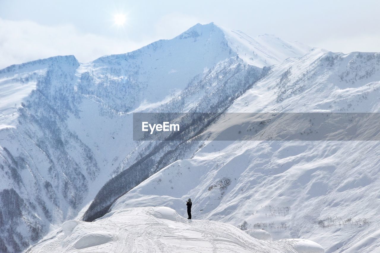 Man standing on snowcapped mountains against sky