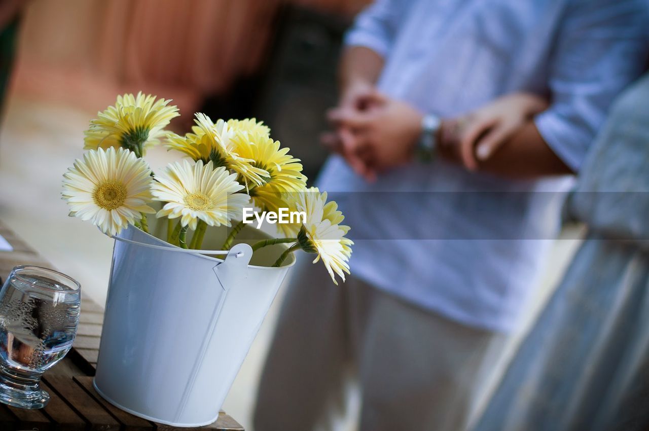 Close-up of yellow flowers in container against couple