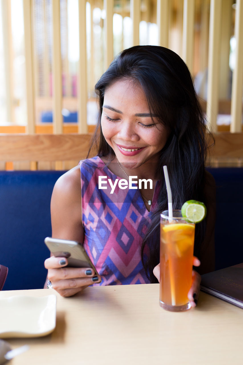 Young woman using phone in restaurant