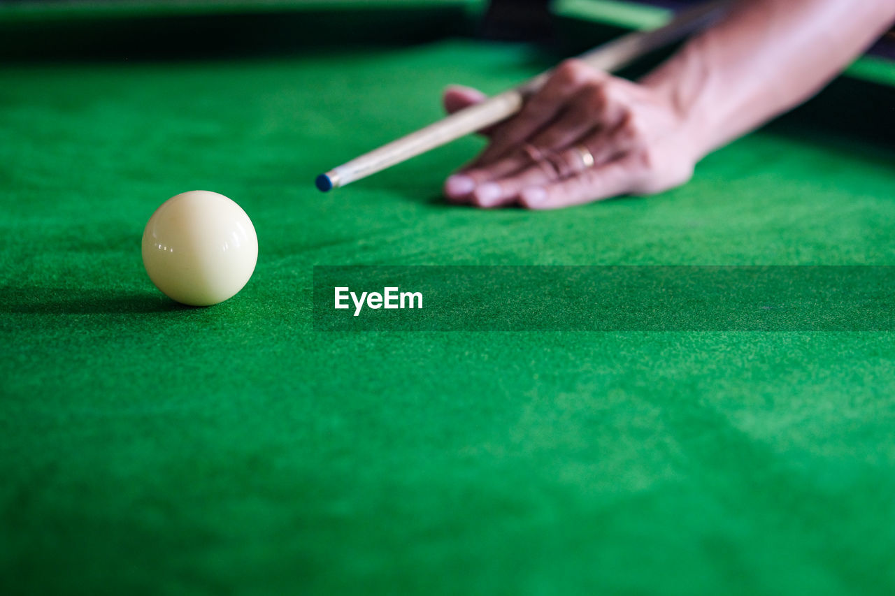 Cropped hand of man playing pool ball