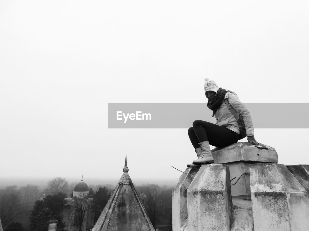 Woman sitting on built structure of historical temple