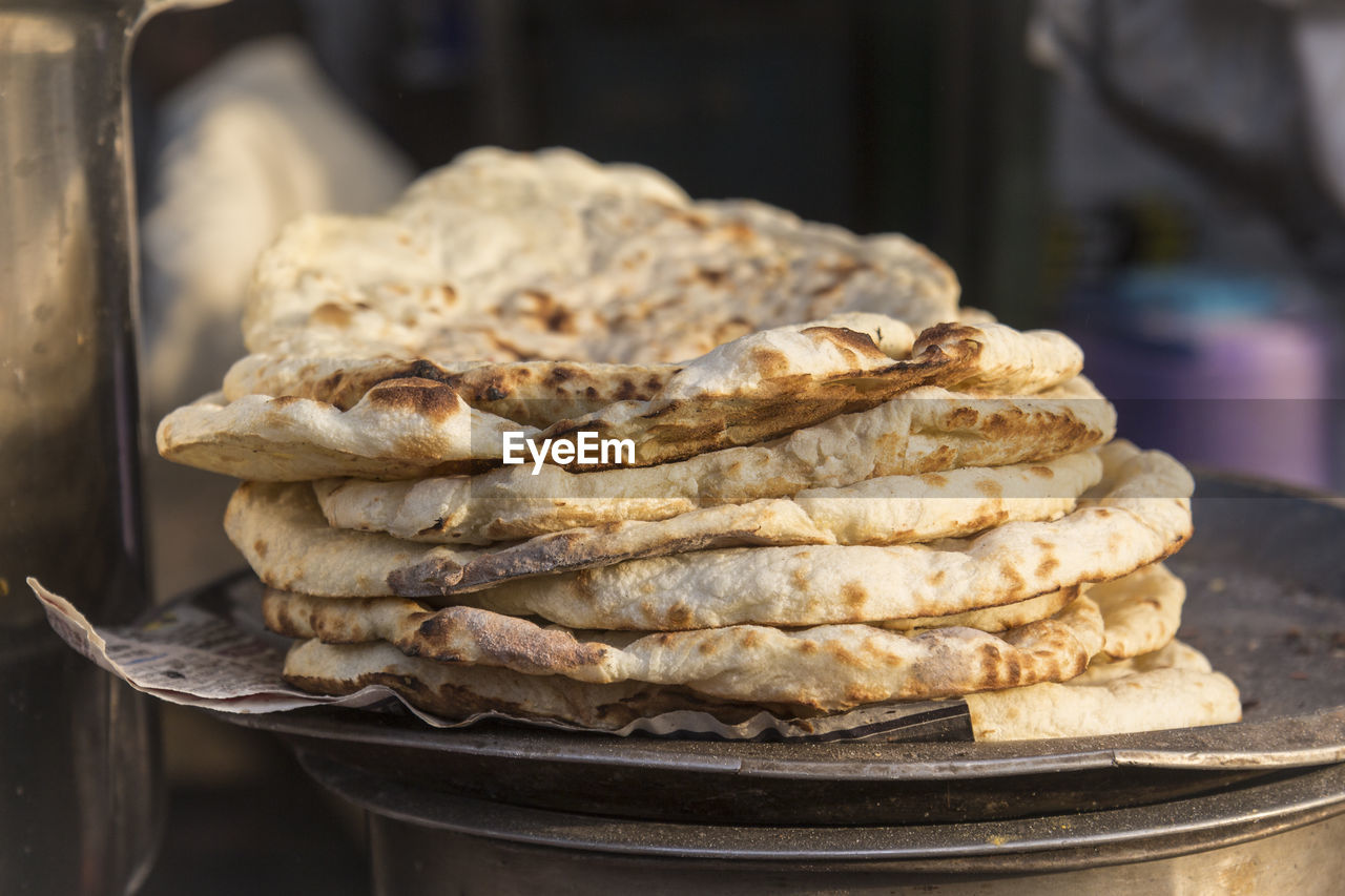 Roti pile in street food stall in marketplace of delhi, india