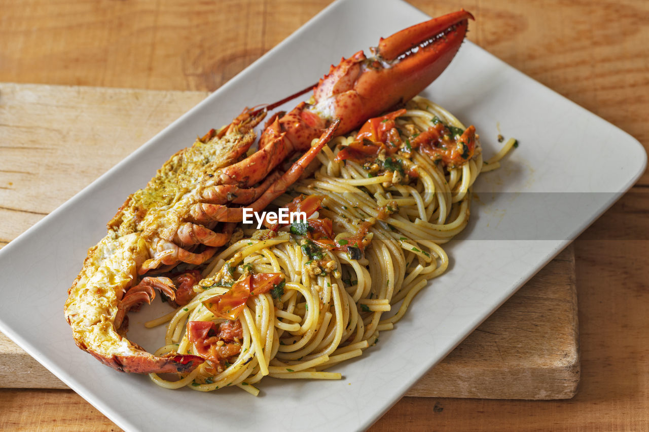 Rectangular plate with plenty of spaghetti and half a lobster.