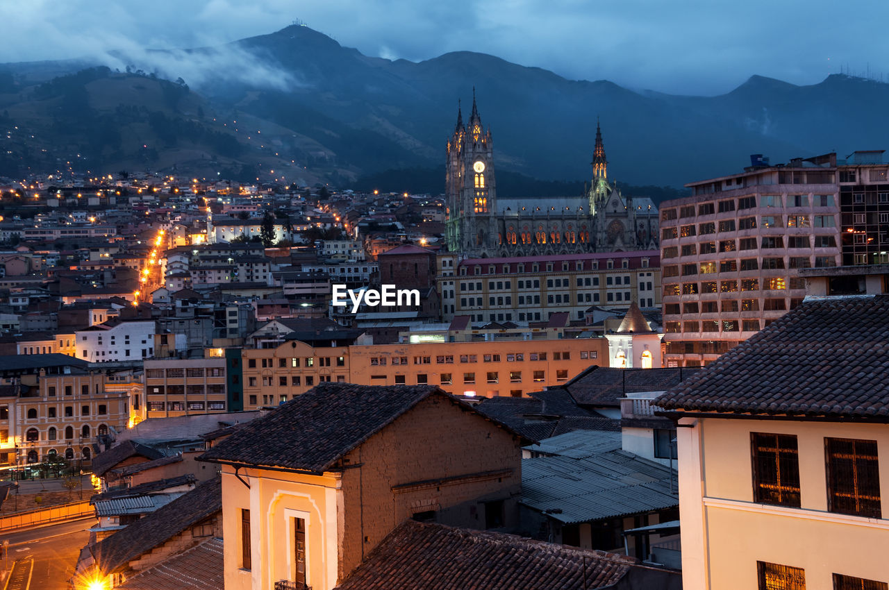 Illuminated city against mountains at twilight