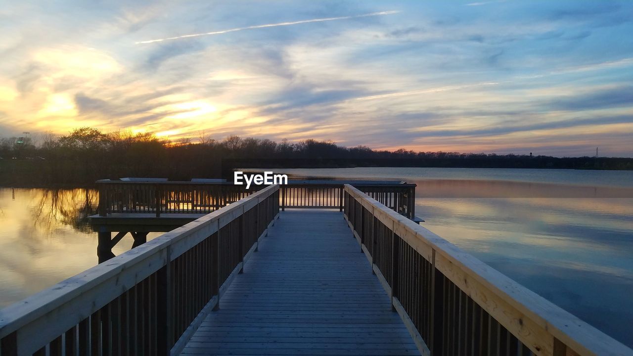 Pier over lake against sky during sunset