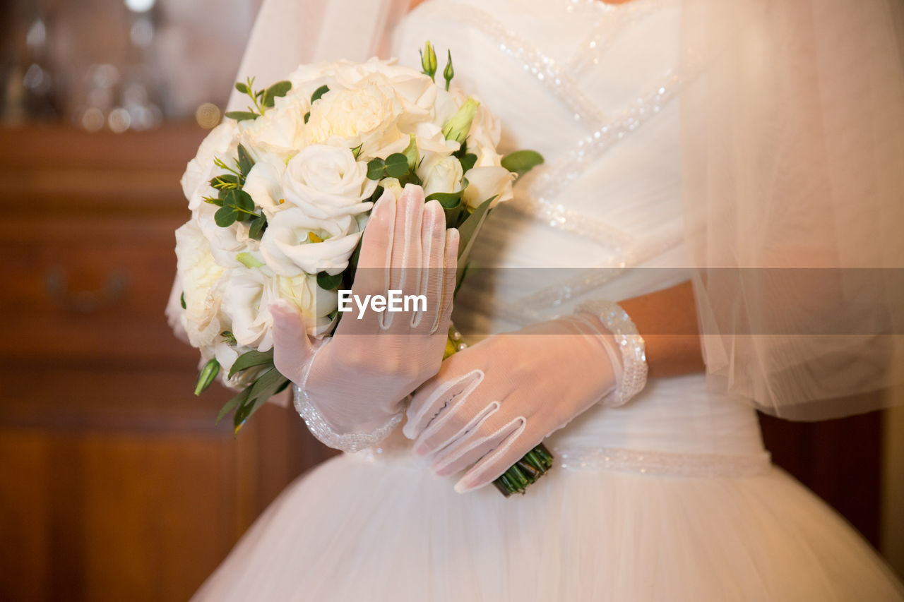 Midsection of bride holding bouquet during wedding
