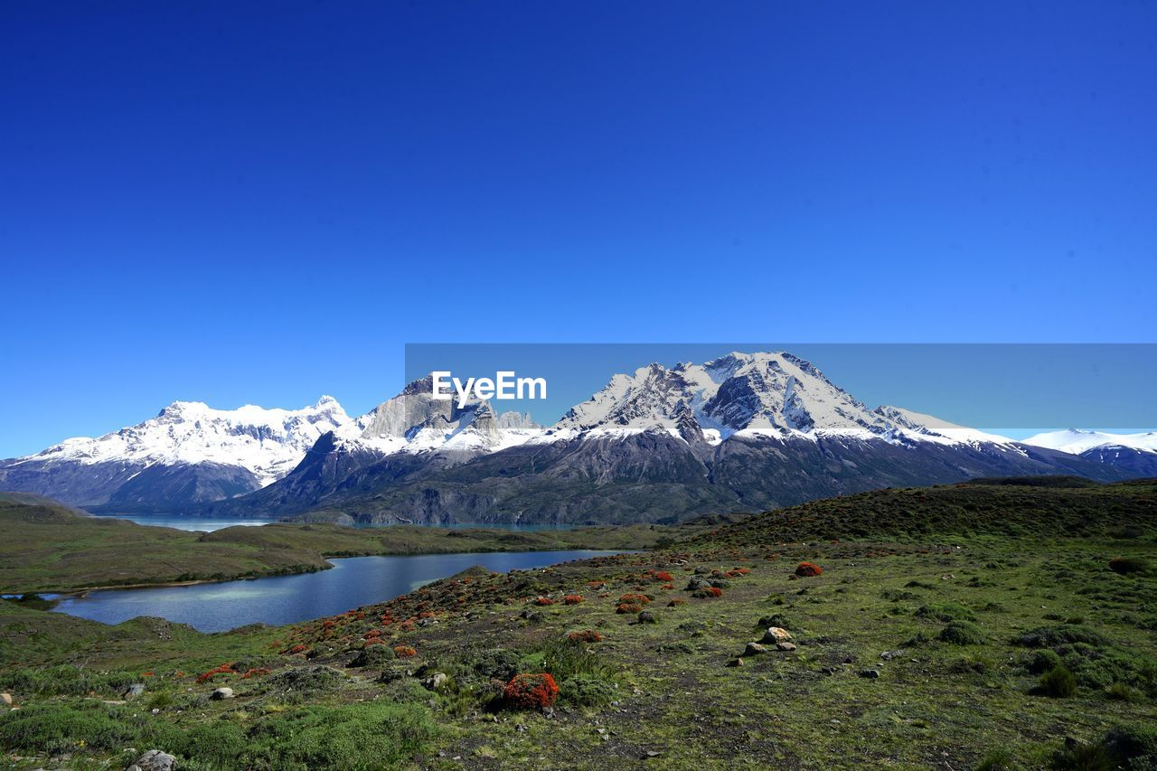 Scenic view of snowcapped mountains against clear blue sky