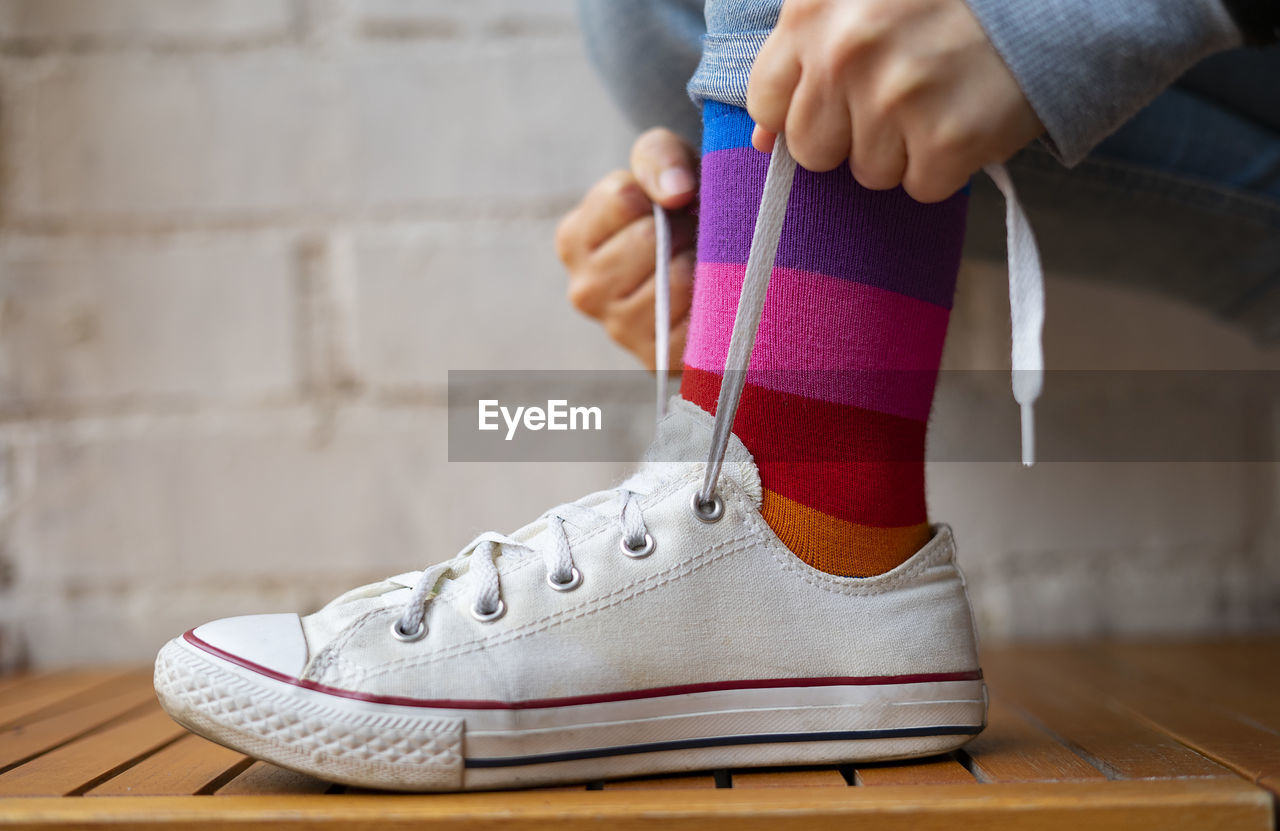 Woman tying laces of her white sneaker.