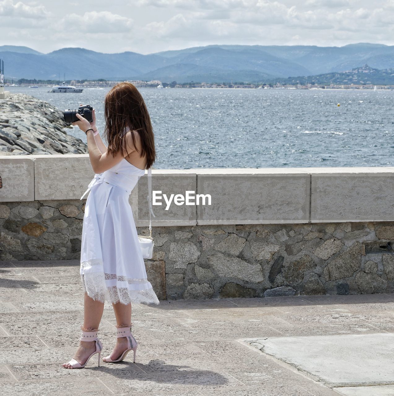 Side view of woman photographing while standing on promenade