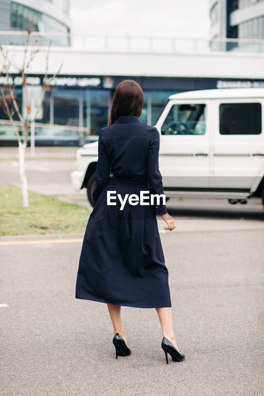 Rear view of woman with umbrella walking in city