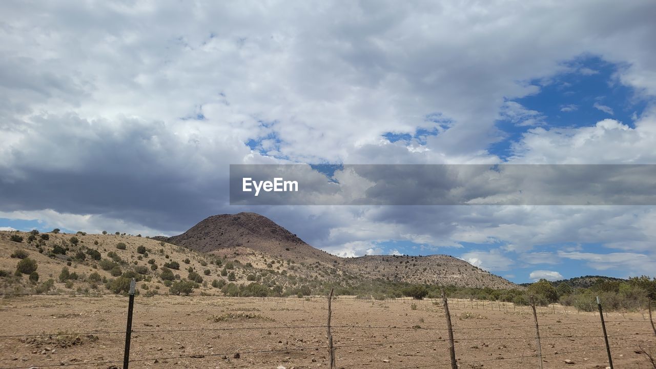 cloud, landscape, sky, environment, natural environment, scenics - nature, land, nature, mountain, soil, field, desert, plateau, plain, no people, fence, horizon, valley, beauty in nature, rural area, non-urban scene, outdoors, day, arid climate, climate, travel, wilderness, mountain range, steppe, semi-arid, travel destinations, tranquility, tranquil scene, plant, dry, rural scene, remote, blue