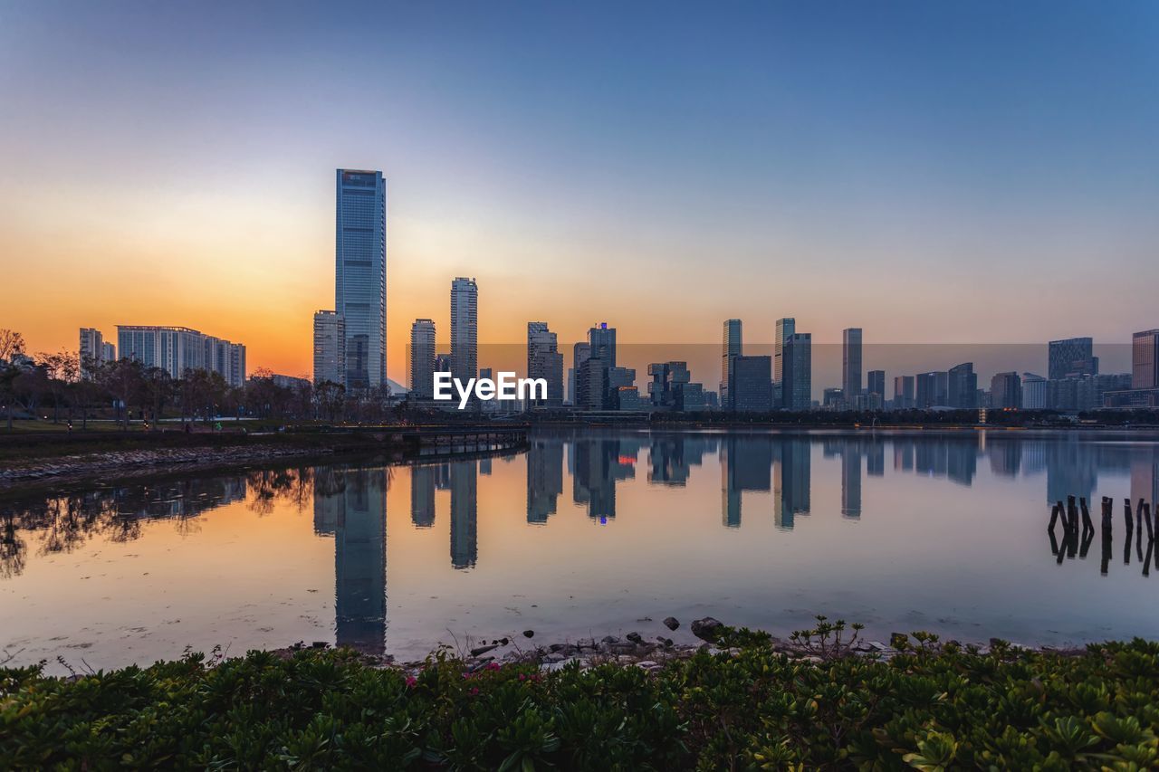 REFLECTION OF BUILDINGS IN CITY AGAINST SKY