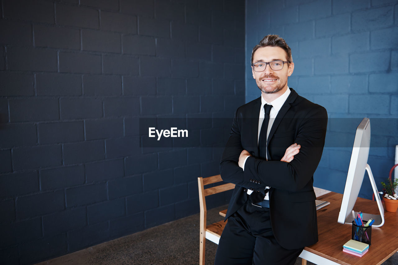 Portrait of a smiling young man sitting against wall