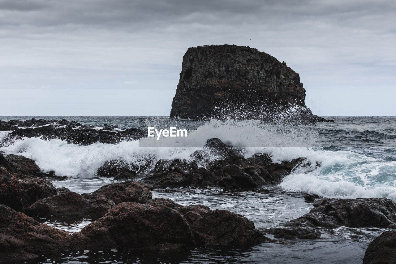 Rock formation in sea against sky