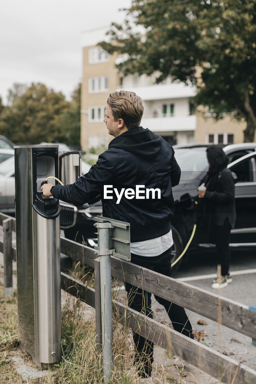 Man connecting cable at electric car charging station