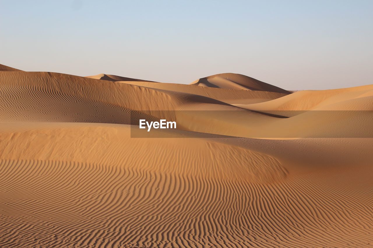 Sand dunes in desert against clear sky