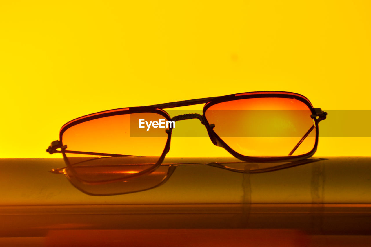 eyewear, yellow, glasses, fashion, eyeglasses, reflection, vision care, single object, no people, brown, sunglasses, glass, indoors, close-up, fashion accessory, cool attitude, orange color, personal accessory, copy space, studio shot, transparent, drinking glass