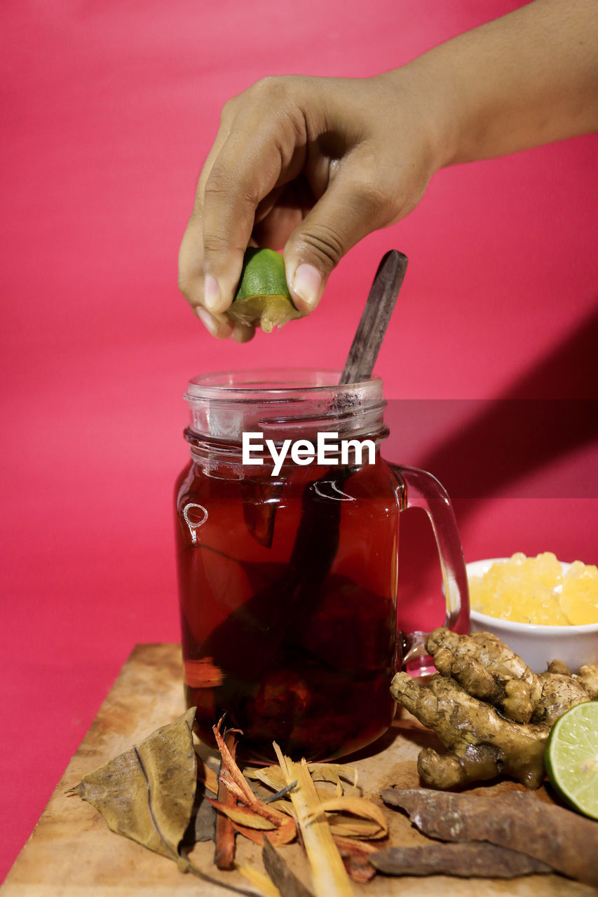 CLOSE-UP OF HAND HOLDING DRINK IN GLASS JAR