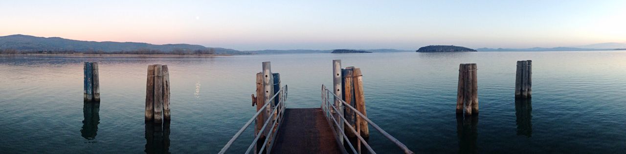 Wooden posts in sea against sky