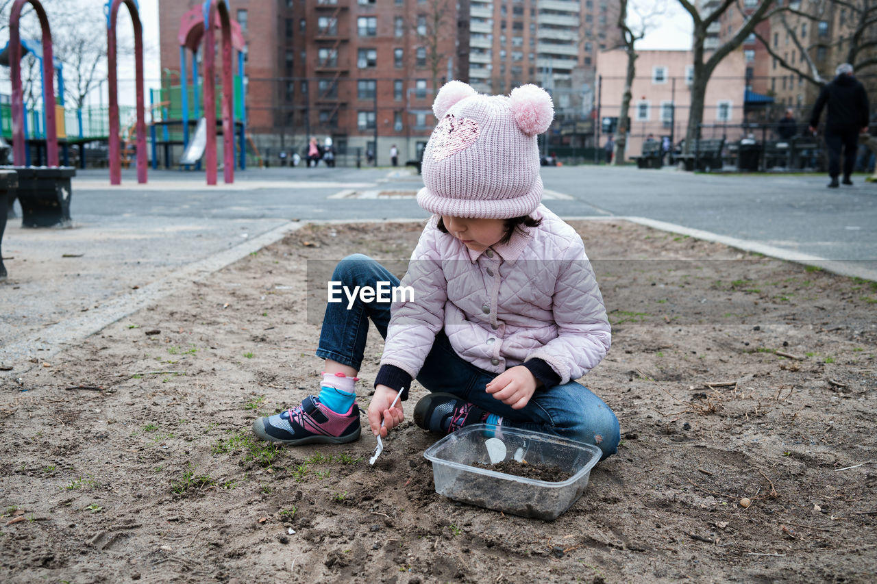 Girl digging in the dirt on the playground on a foggy fall day