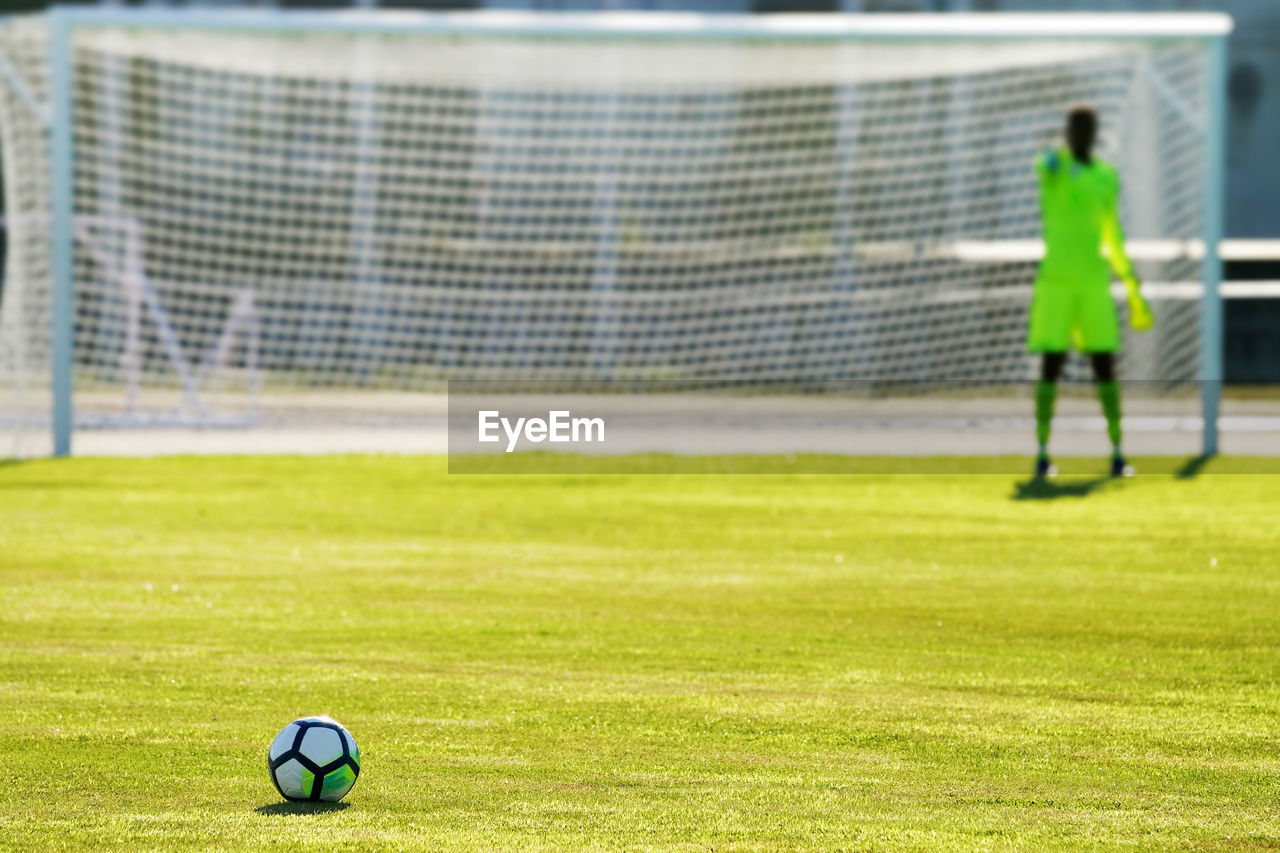 Soccer ball on playing field against goal post