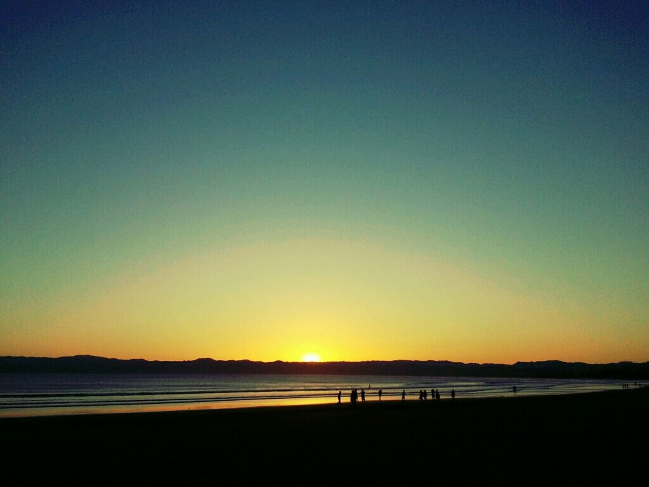 Scenic view of beach against clear sky during sunset