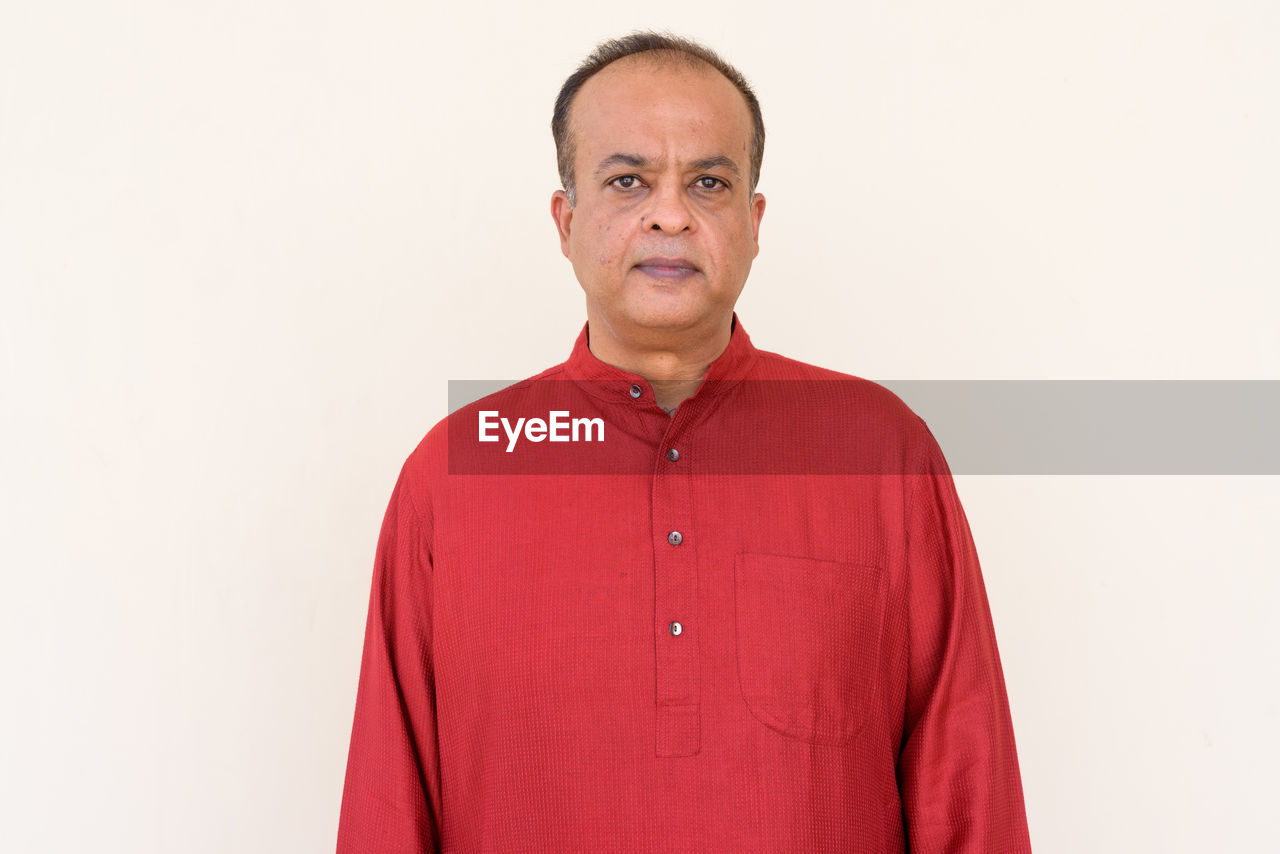 PORTRAIT OF MAN STANDING AGAINST GRAY BACKGROUND