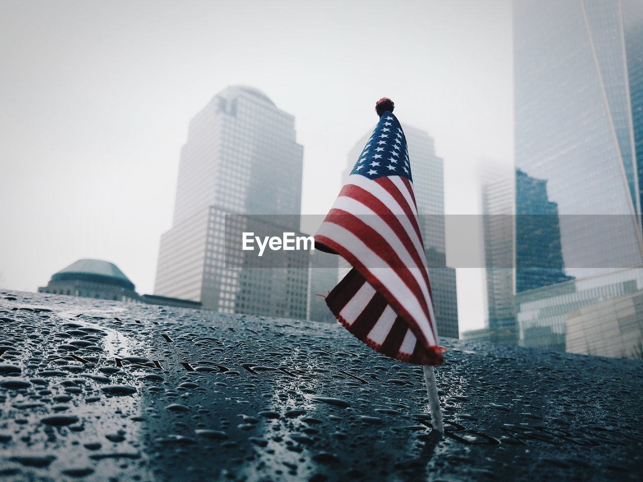 Low angle view american flag by buildings during rainy season