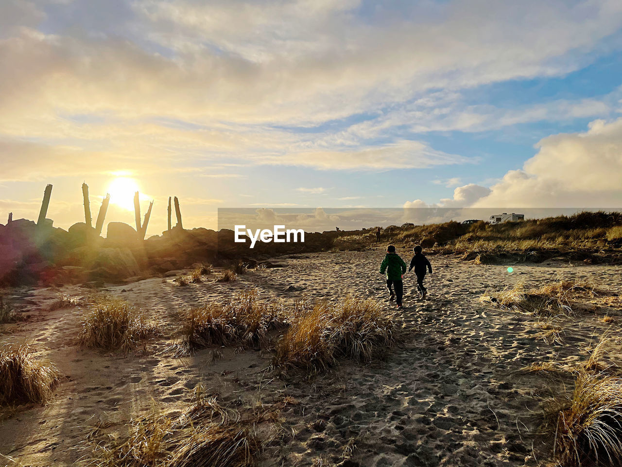 People standing on beach against sky during sunset