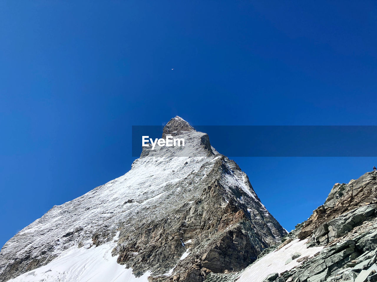 Low angle view of snowcapped mountains against clear blue sky, trail to the summit  with helicopter 