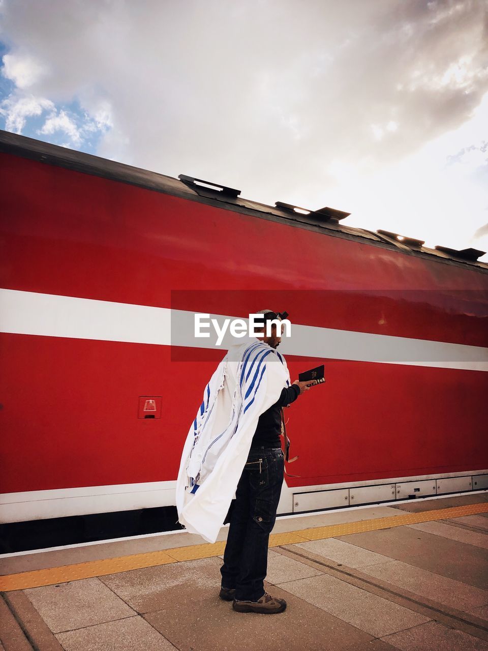 FULL LENGTH OF MAN STANDING ON RED UMBRELLA AGAINST SKY