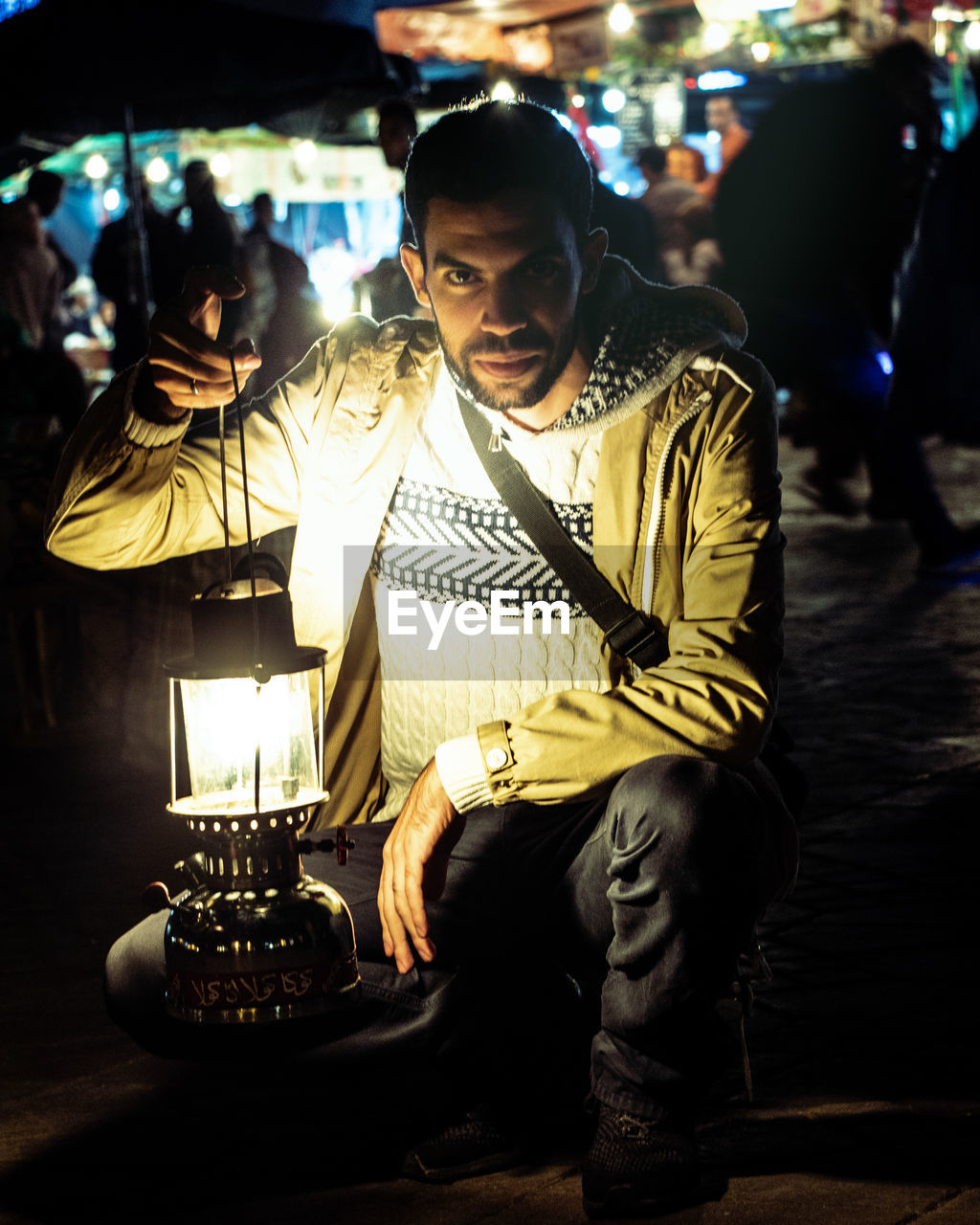 Portrait of man holding illuminated gas lamp at night