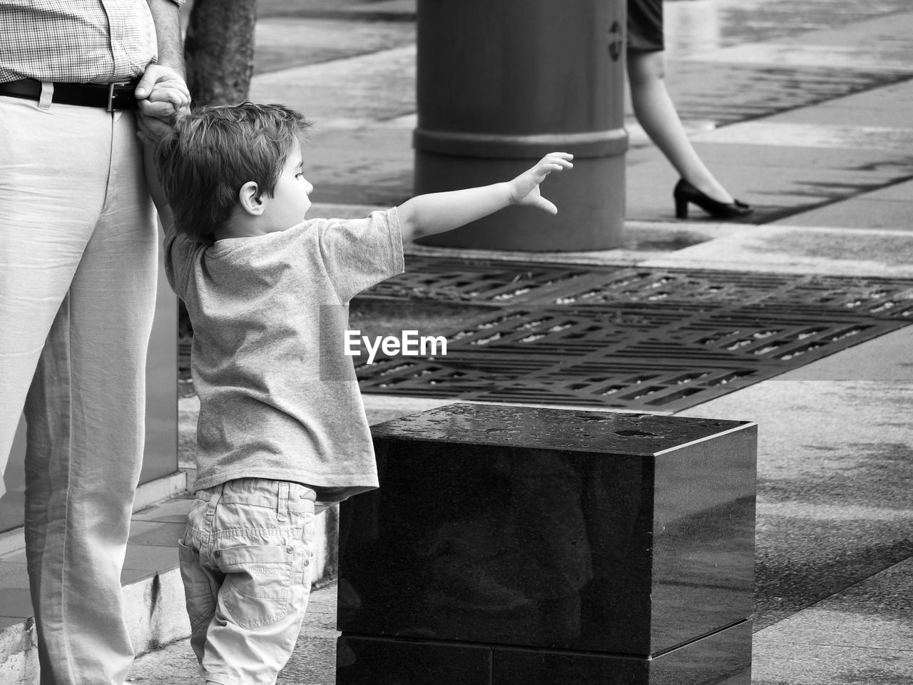 Cute boy with father standing on street in city