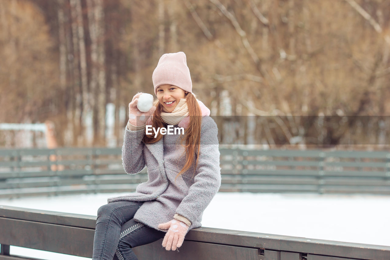 women, adult, clothing, hat, happiness, winter, young adult, one person, smiling, lifestyles, emotion, female, warm clothing, relaxation, sitting, cold temperature, nature, positive emotion, spring, leisure activity, autumn, portrait photography, knit hat, portrait, city, enjoyment, casual clothing, architecture, cheerful, coffee, bench, copy space, person, photo shoot, day, outdoors, blond hair, human face, drink, looking, city life, food and drink, fun, cup, long hair, railing, hairstyle, bridge, recreation