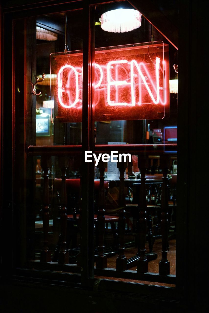 Illuminated open text at store during night