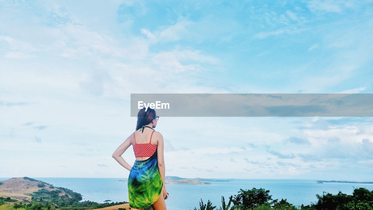 Rear view of woman standing against sea