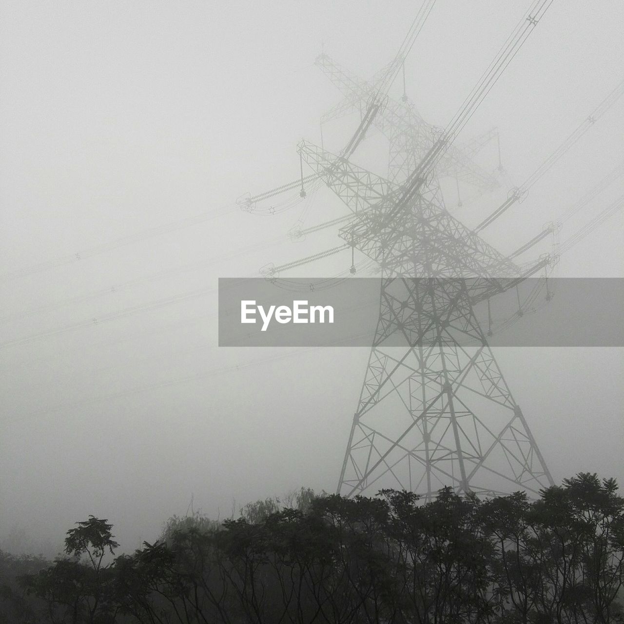 Low angle view of electricity pylon against sky during foggy weather